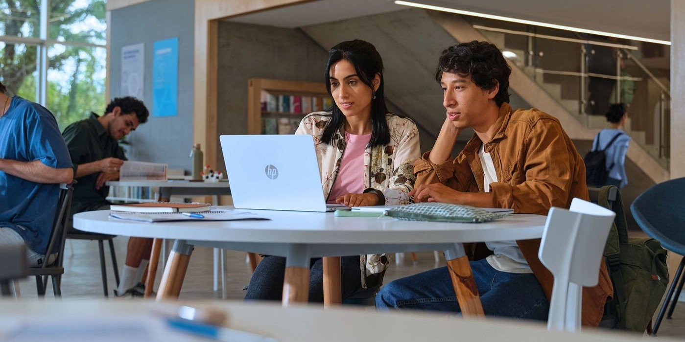Estudiantes universitarios colaborando en proyectos acad&eacute;micos con notebook HP en biblioteca o &aacute;rea de estudio